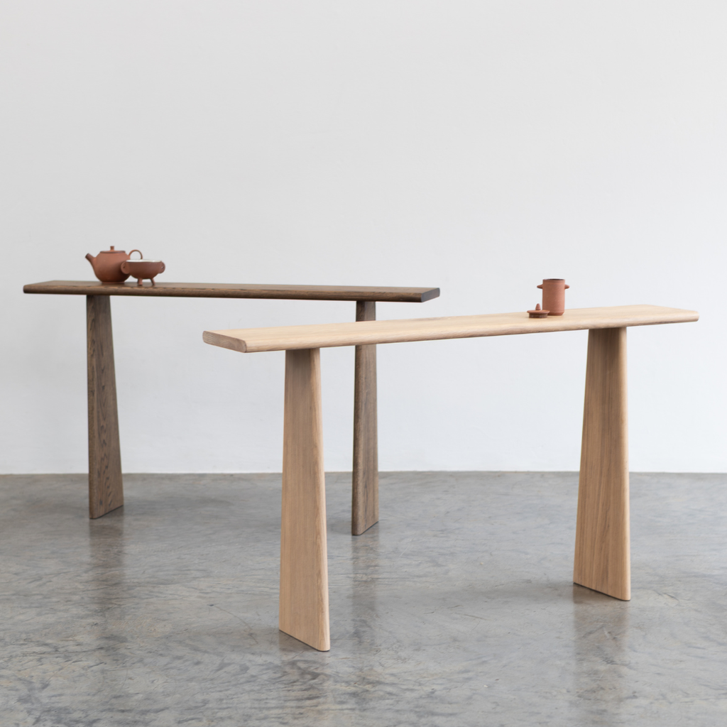 Two wooden entryway tables with minimalistic design on a gray floor.