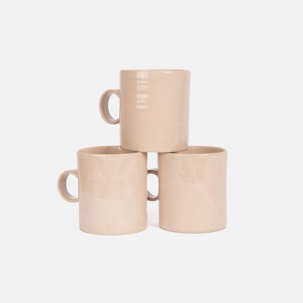 Three beige ceramic mugs stacked on a white background