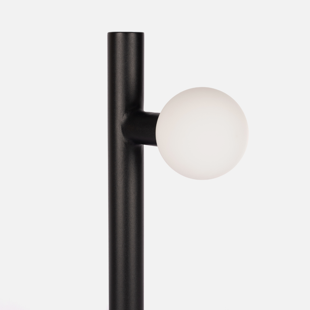 Black wall lamp with a white spherical bulb on a light gray background
