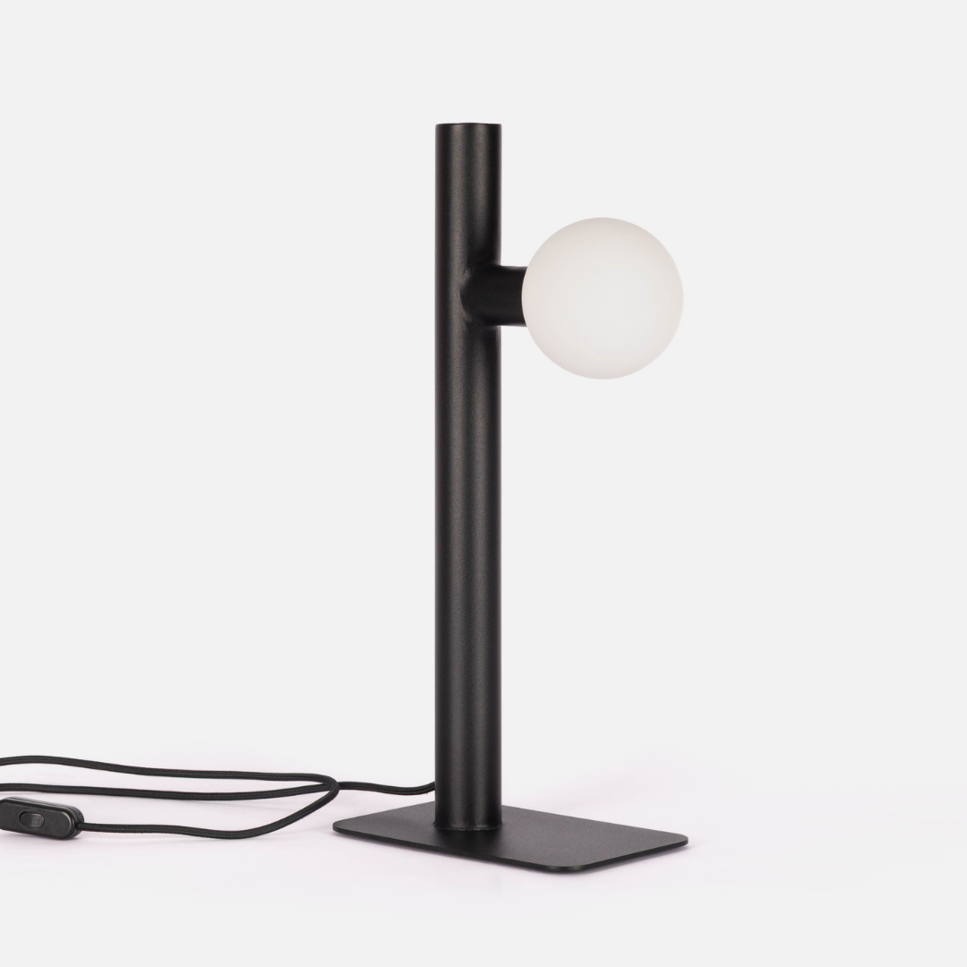 Modern black table lamp with a white globe light on a white background