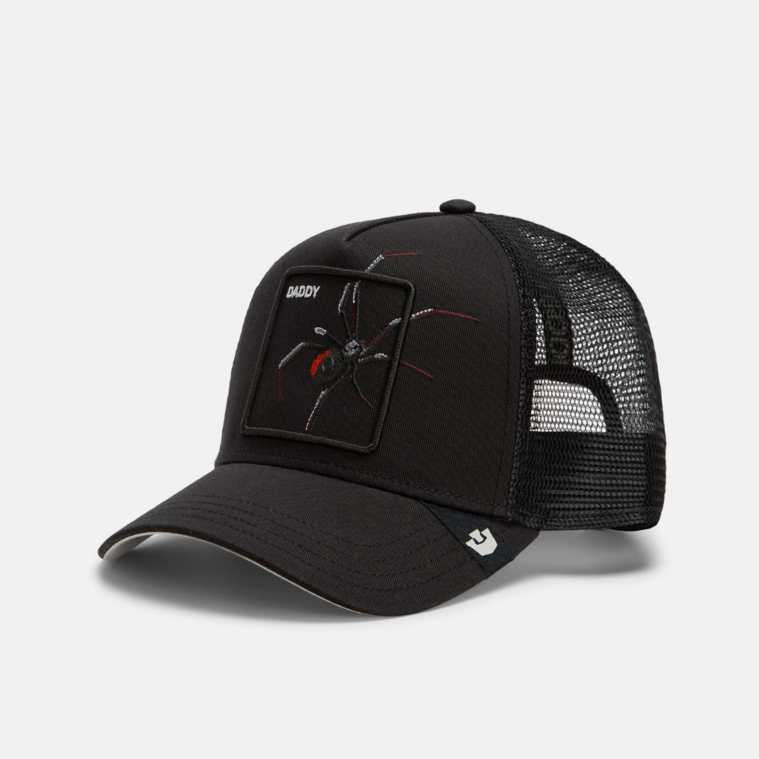A black trucker-style cap with a curved brim, black mesh back, and a rectangular patch on the front featuring a spider graphic and the word 'SHADY'.