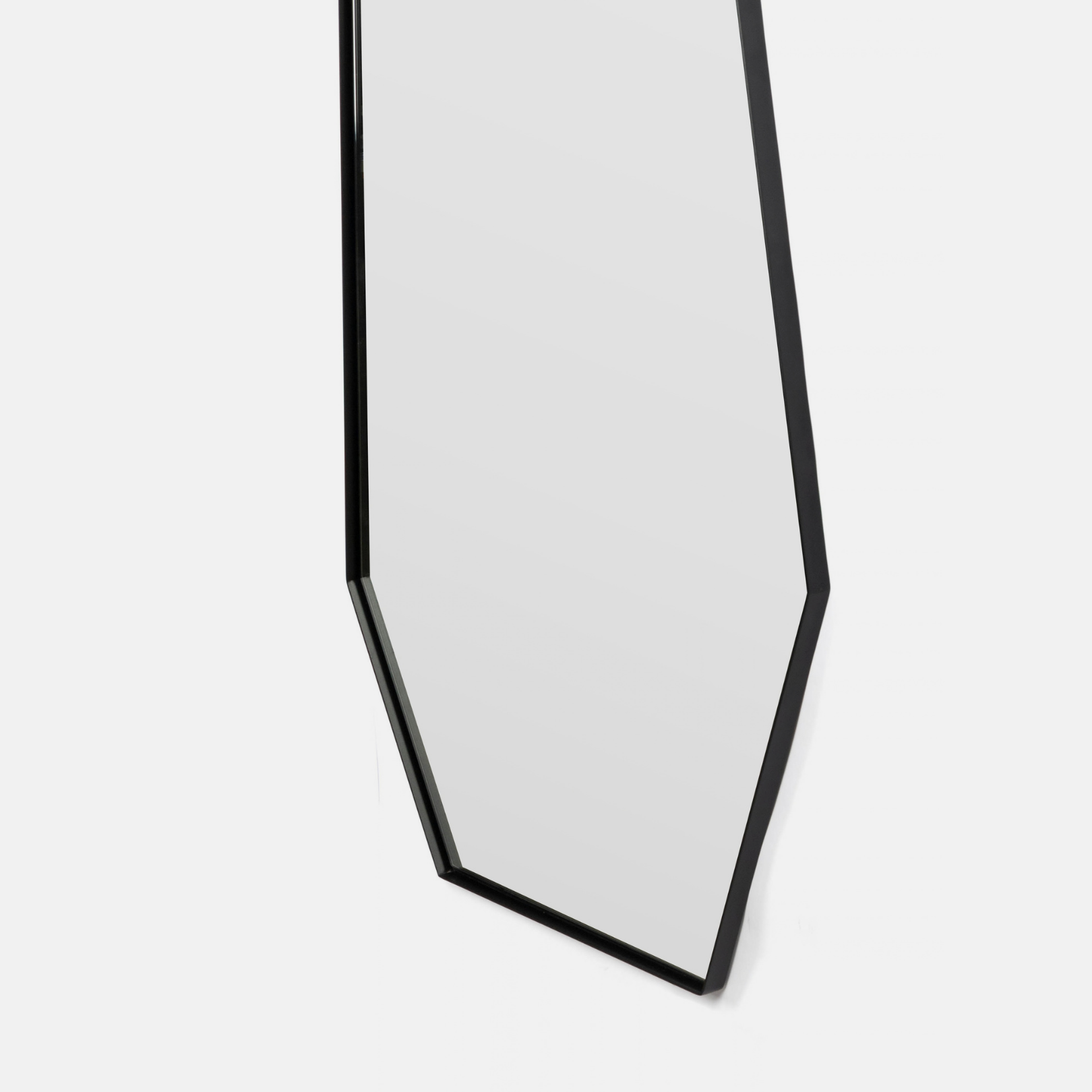 A modern hexagonal wall mirror with a thin black frame, shown against a plain light gray background.