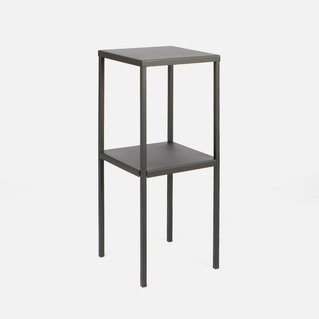 A tall, black, powder-coated steel side table with a rectangular shape and one shelf.